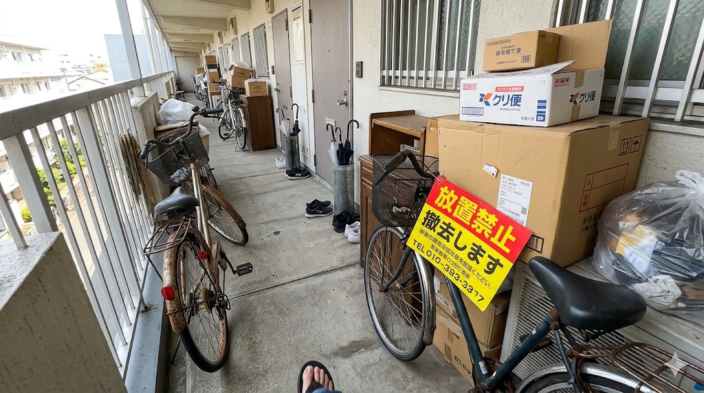 マンション共用廊下に放置された私物・自転車のイメージ