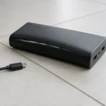 外装が膨らみ合わせ目が開いたモバイルバッテリーと外した充電ケーブル
