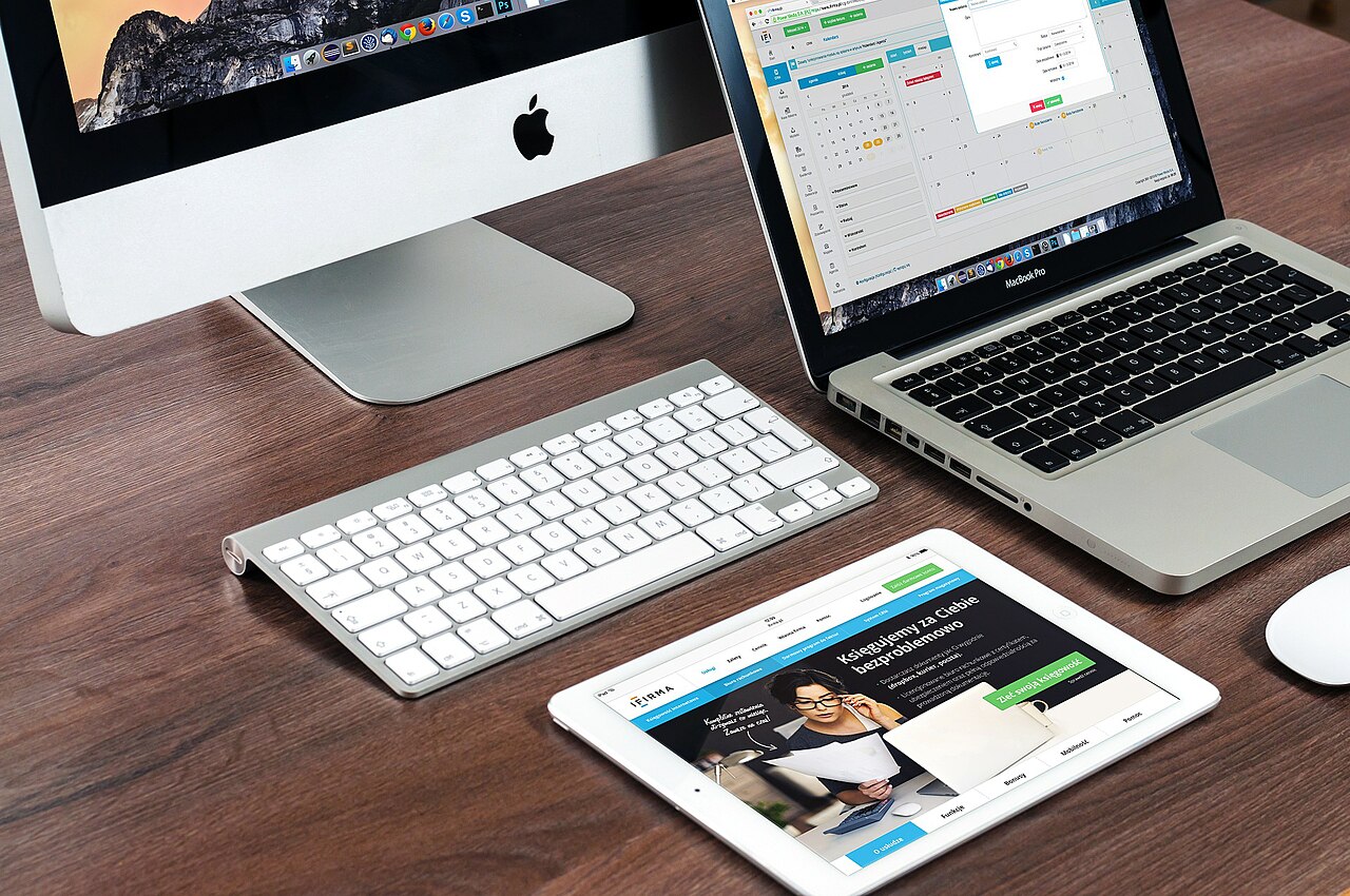 iMac、MacBook、iPadとキーボードが置かれた作業机
