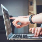 ノートパソコンの画面を指差しながら作業内容を確認する二人の手元